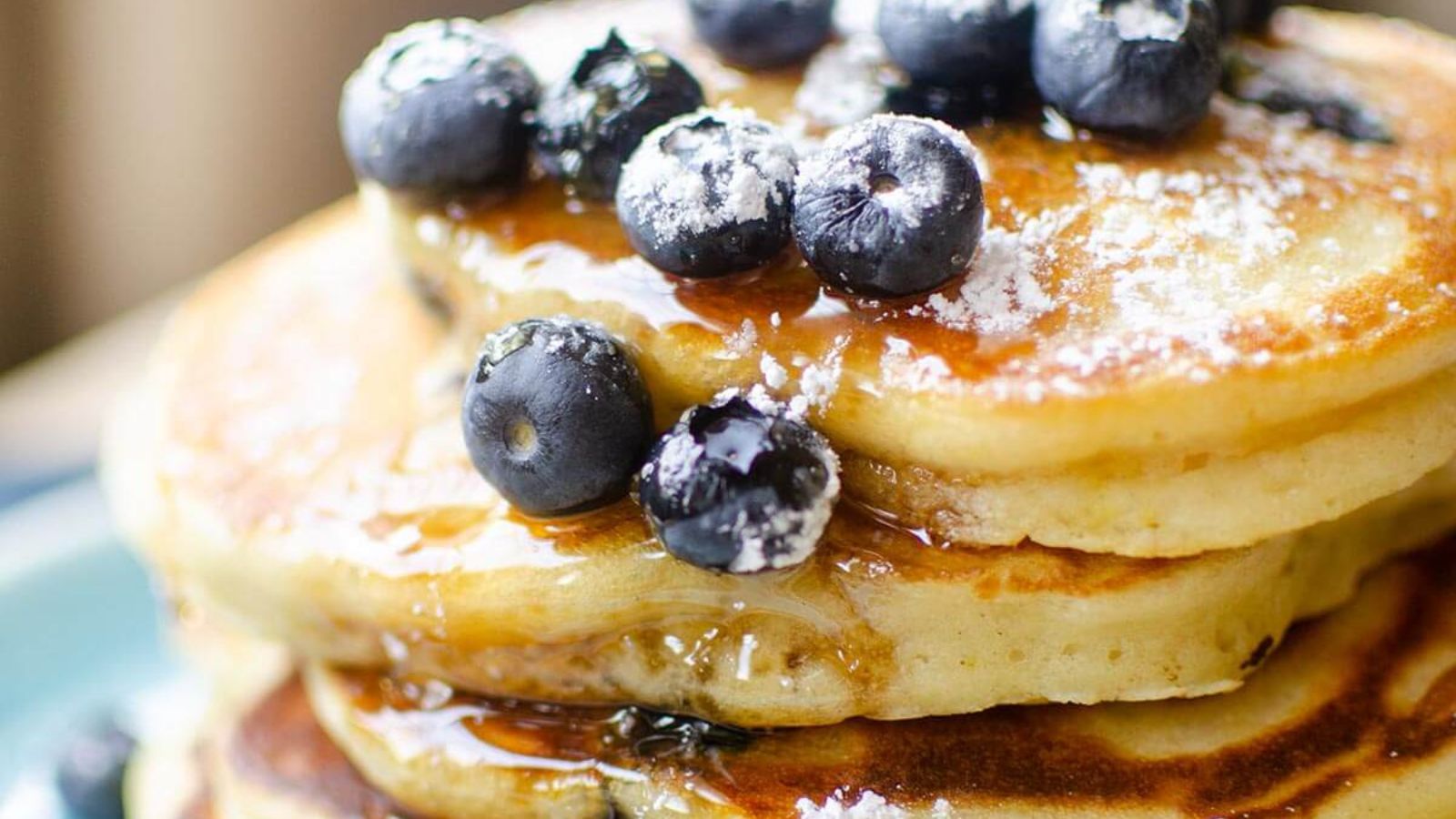 Blueberry Lemon Pancakes stacked on a blue plate.