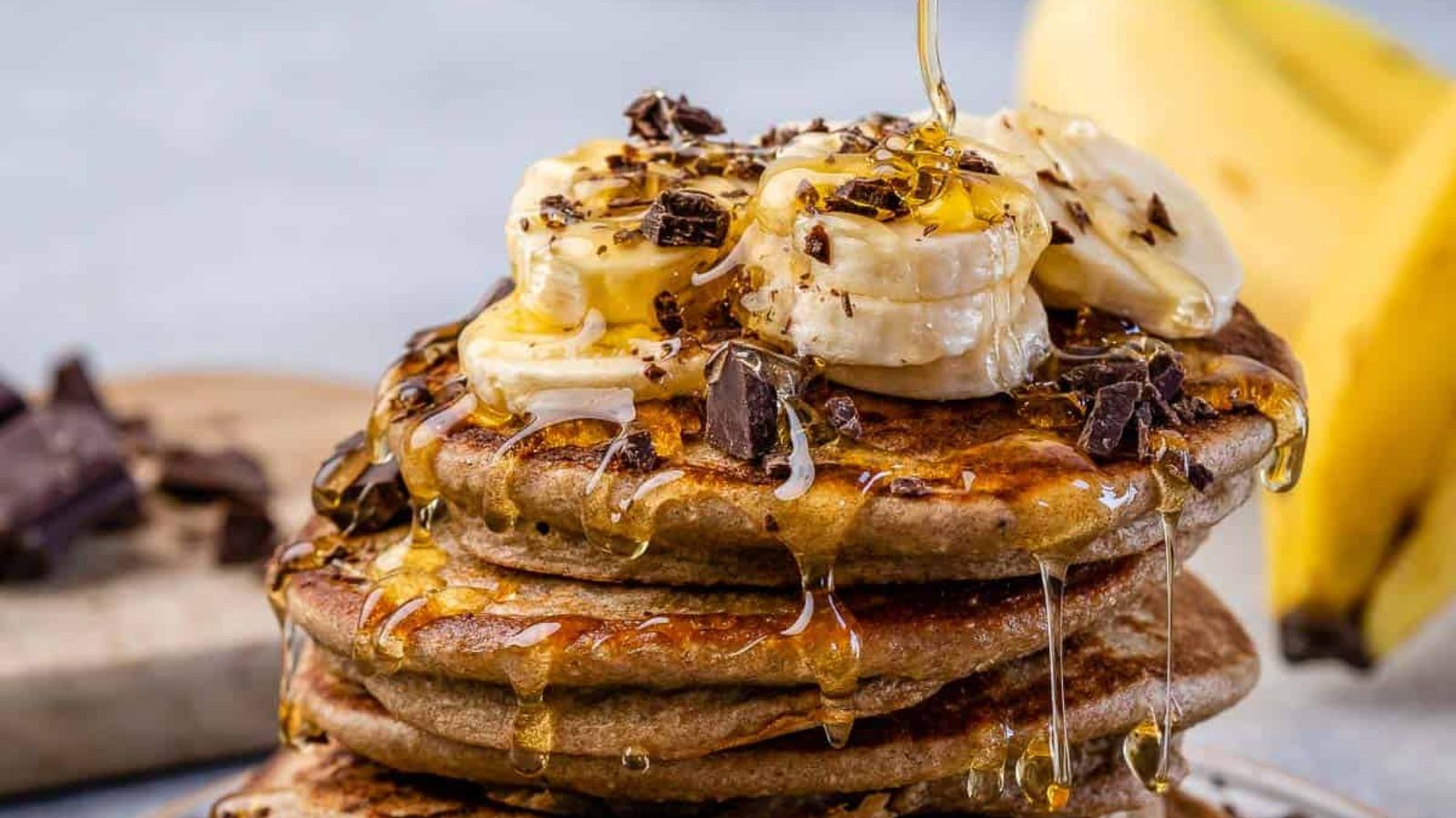 Banana Oatmeal Pancakes with syrup being drizzled over.