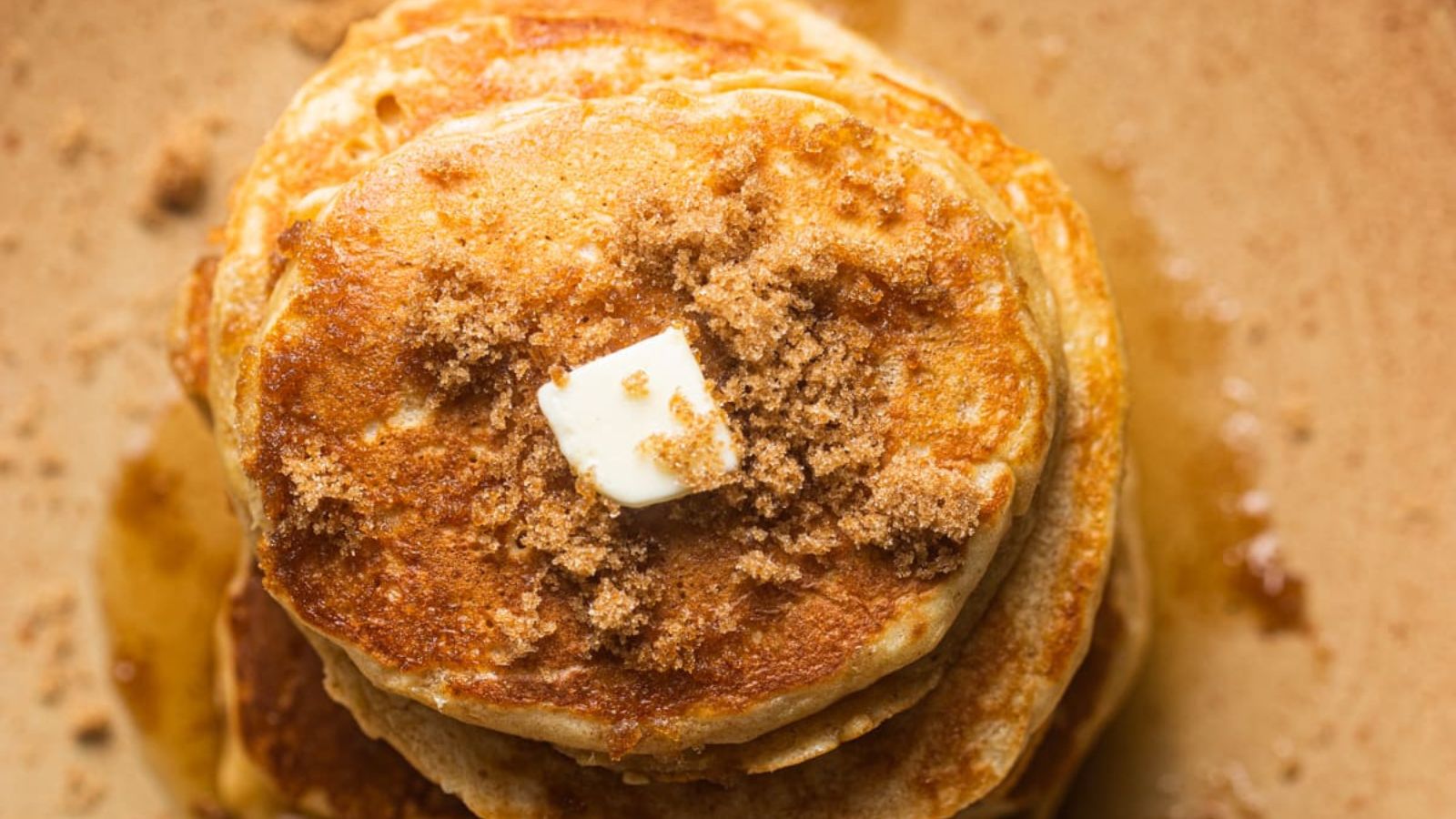 Fluffy Brown Sugar Pancakes stacked and with butter and sugar on top.