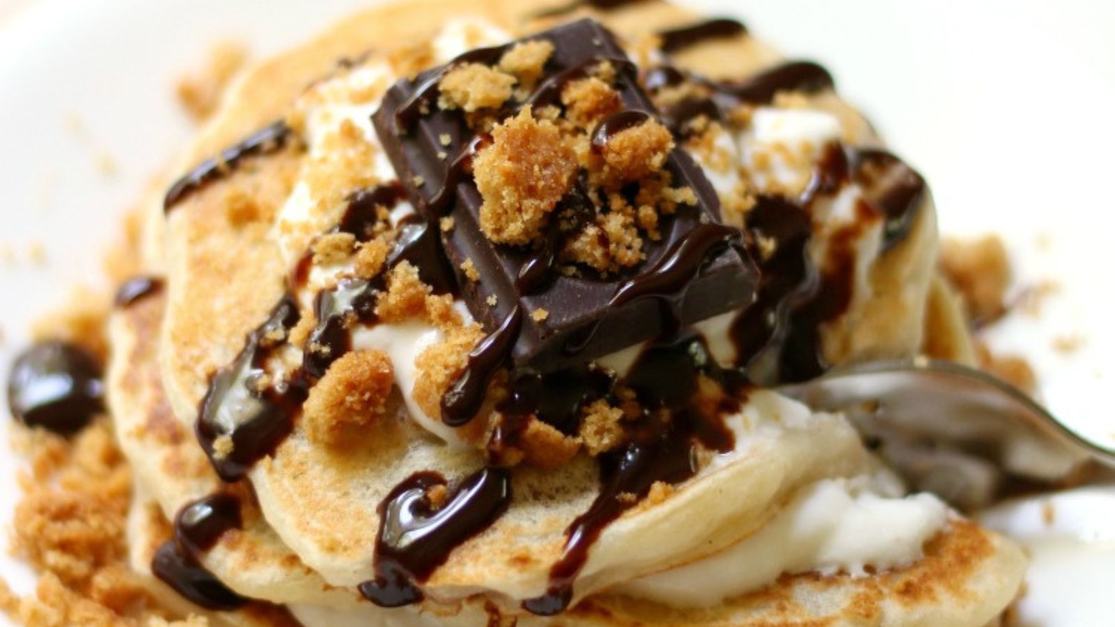 Gluten-Free S'mores Pancakes stacked on a plate with a spoon cutting in.
